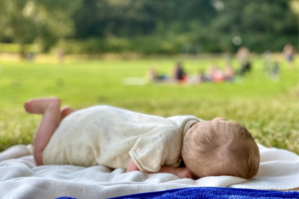 close up foto of baby laying on a blanket in a park