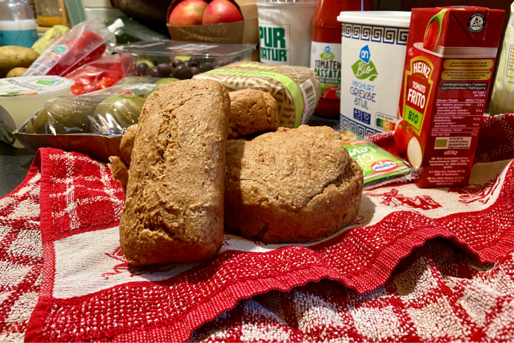 Two breads with other groceries in the background laying on a red towel