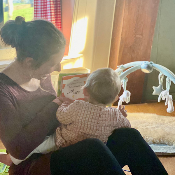 Women sitting with baby on lab on the floor reading a book to baby