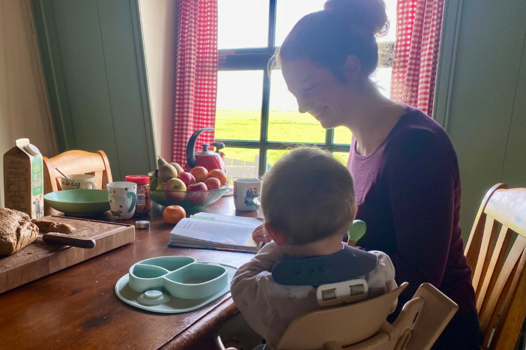 women reading a book to a baby at breakfast table