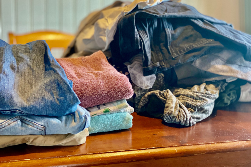 two piles of folded laundry with unfolded laundry at the right 