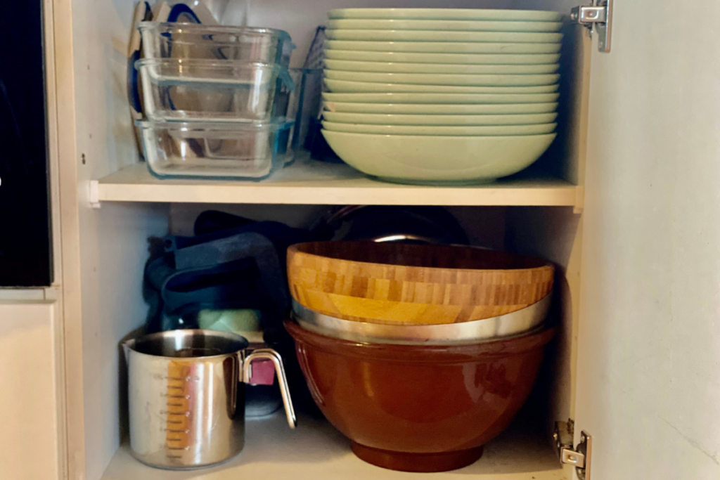 Cabinet with dishes, tupperware, measurement cup and bowls