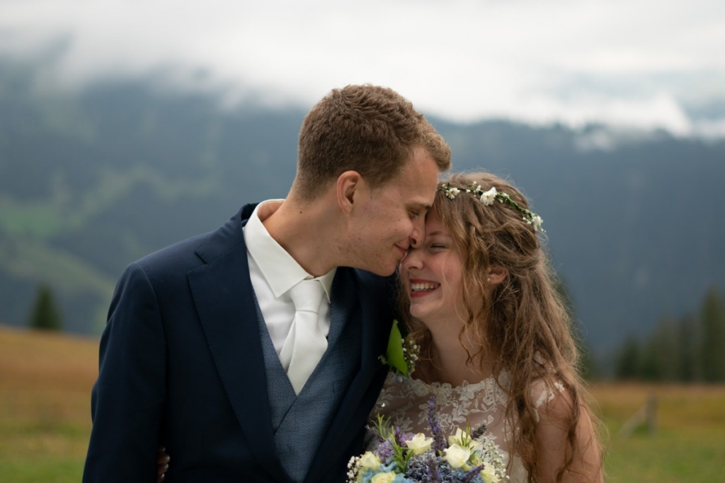 A husband and a wife on their wedding day, husband is pressing his nose unto wife's forehead 