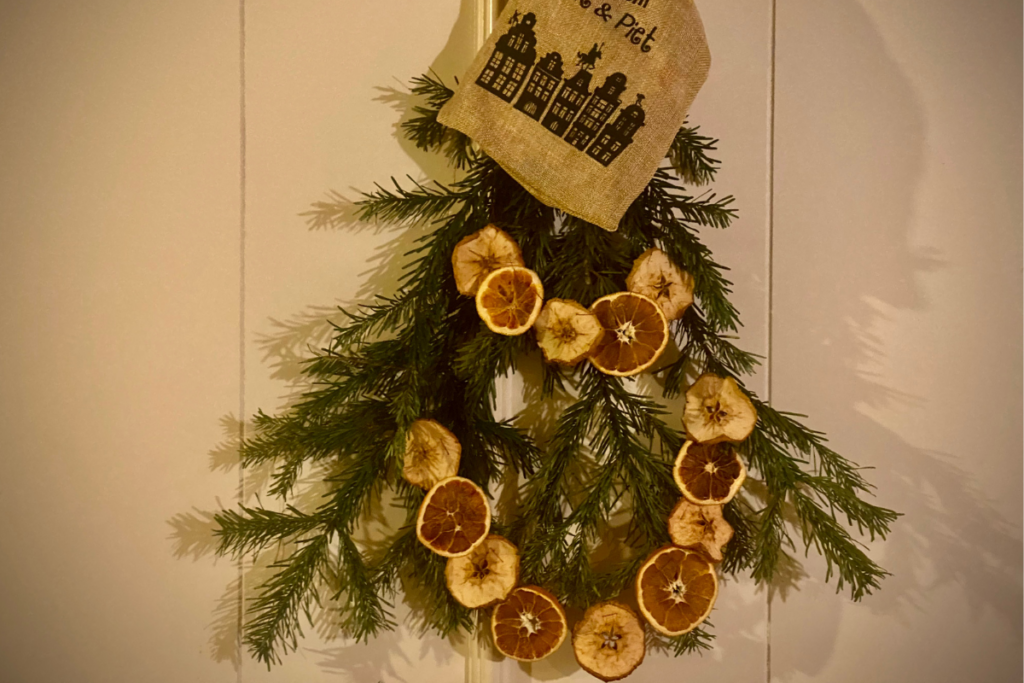 Pine tree branches with orange and apples slices hanging as natural and simple Christmas decoration with white background