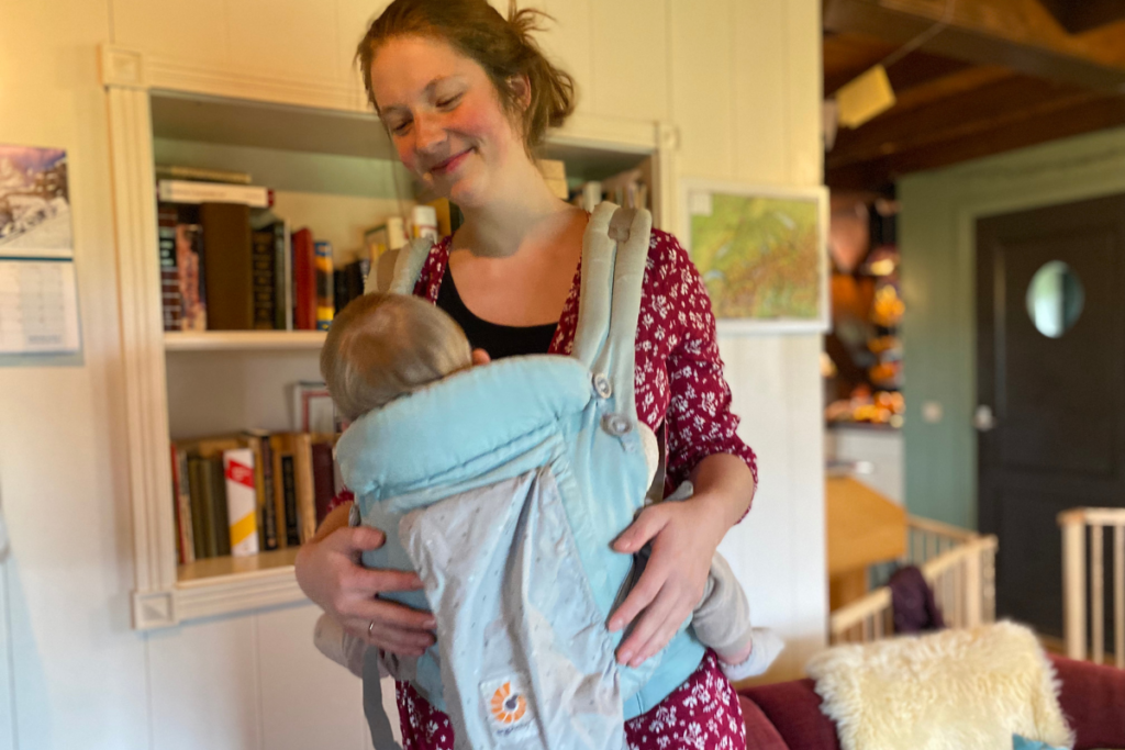 Women breastfeeding  baby in baby carrier smiling