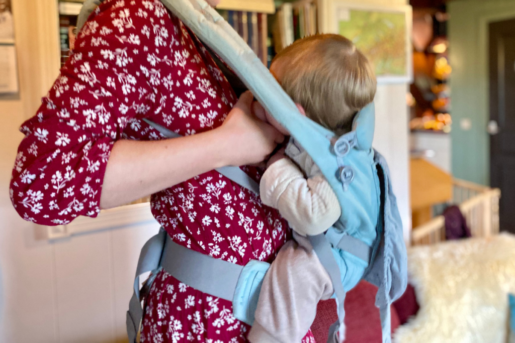 Close op of women breastfeeding in baby carrier in red dress