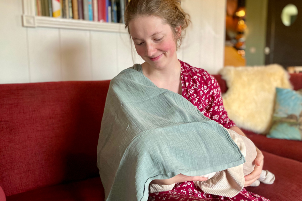 women breastfeeding baby under green cover