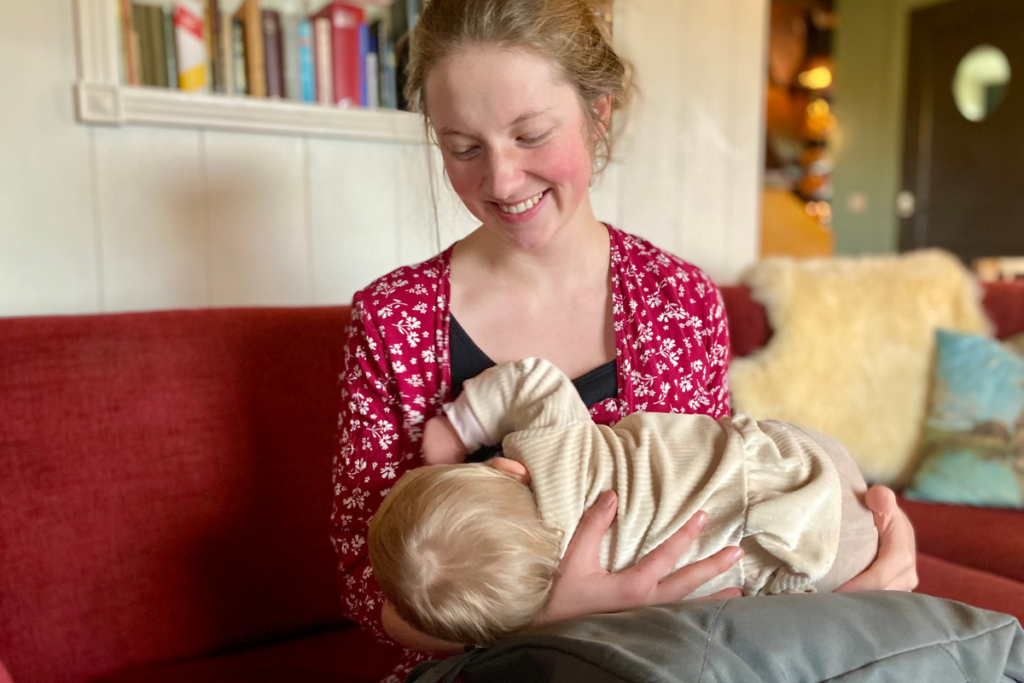 Women discreetly breastfeeding baby (in public) with red dress on