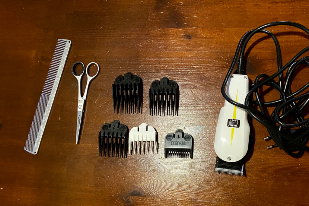 comb, scissors and clipper with length adjustment peaces from the top with wooden background