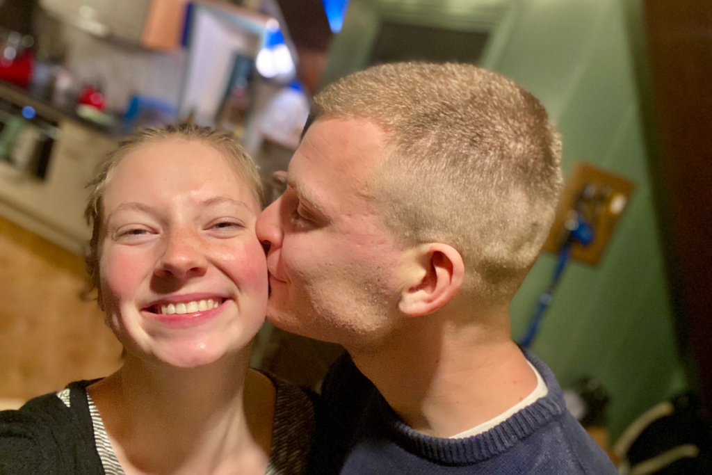 Selfie of a man kissing a women at the cheek laughing into the camera