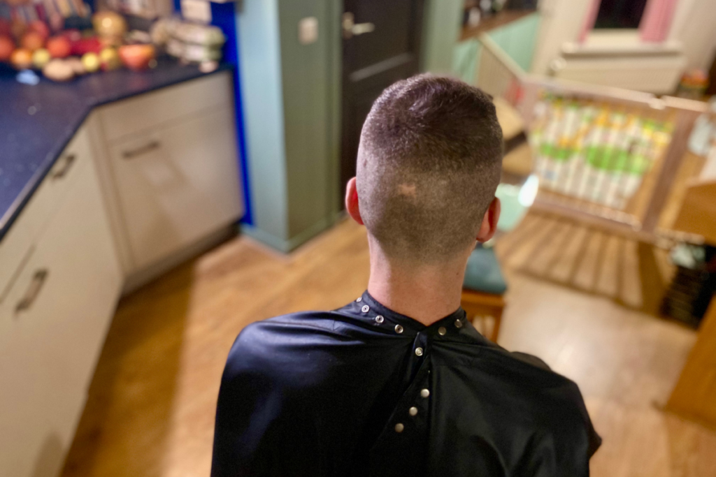 close up from the back man wearing a barber cloak with shaved head