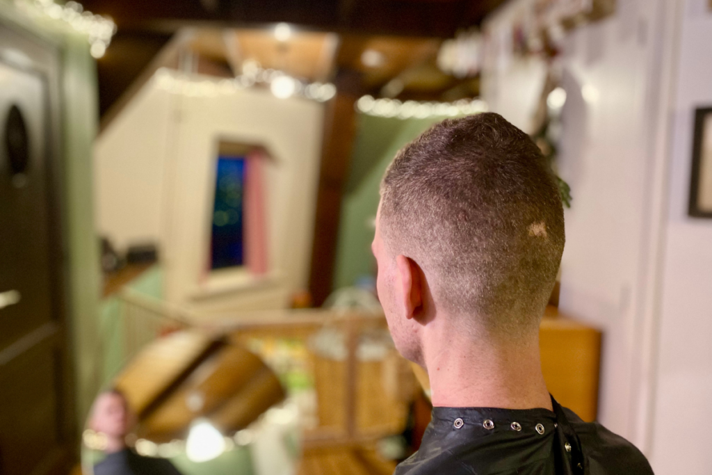 man wearing a barber cape looking into a mirror