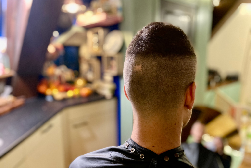 man wearing a barber cloak with shaved head up to top hear line