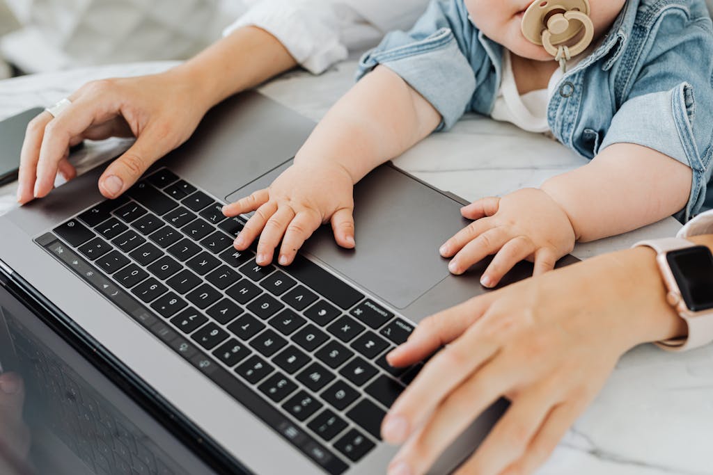 A parent and baby engaging with a laptop keyboard together, focusing on technology and bonding.