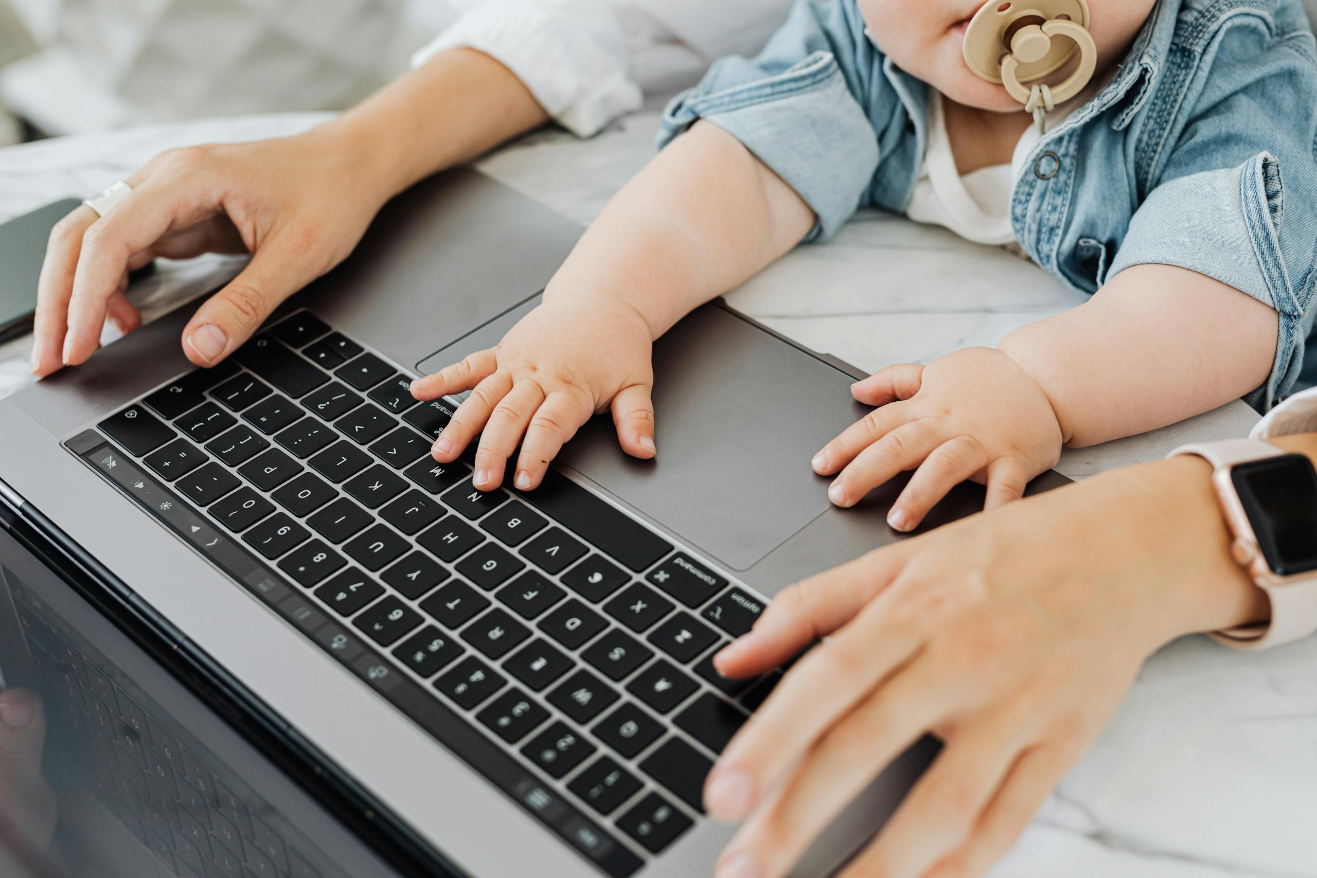 A parent and baby engaging with a laptop keyboard together, focusing on technology and bonding.