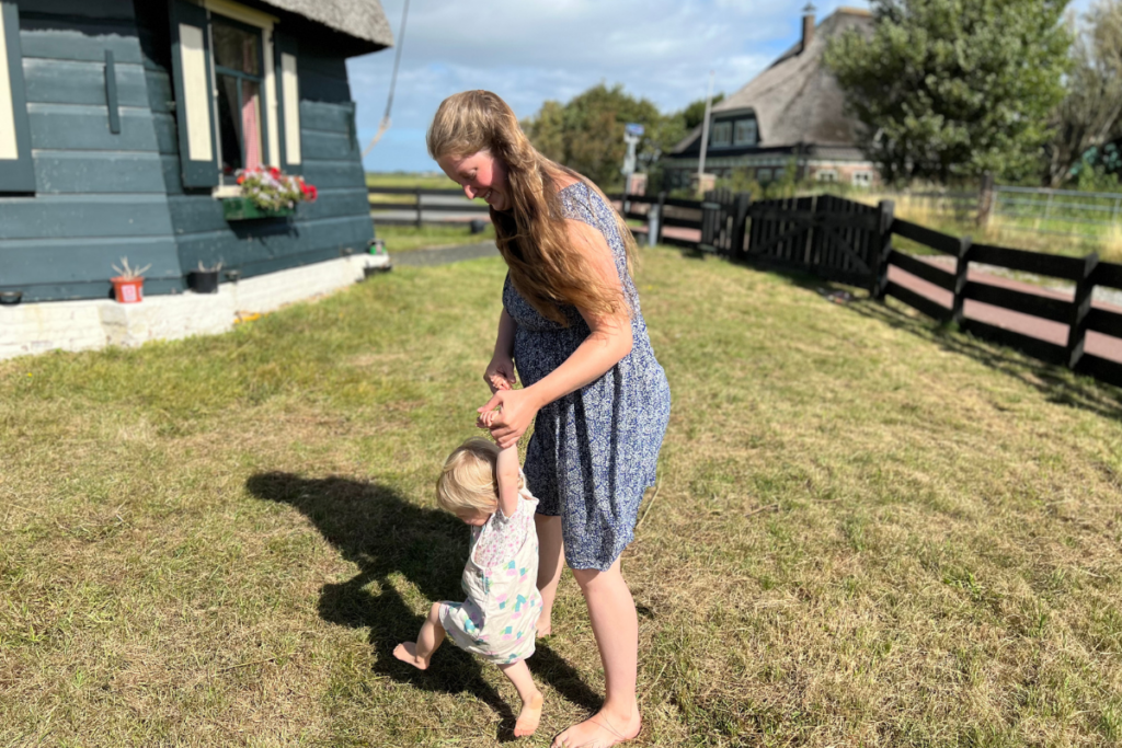 pregnant woman walking on grass with a toddler girl on her hands